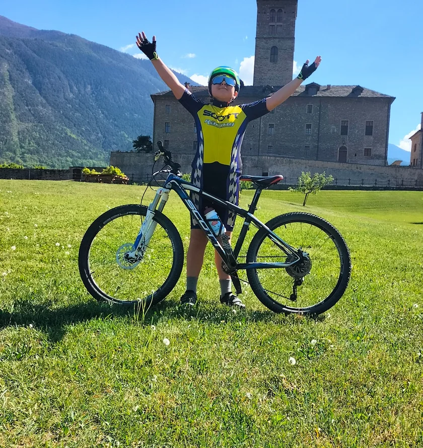 Valerio con la sua mountain bike davanti a un castello valdostano